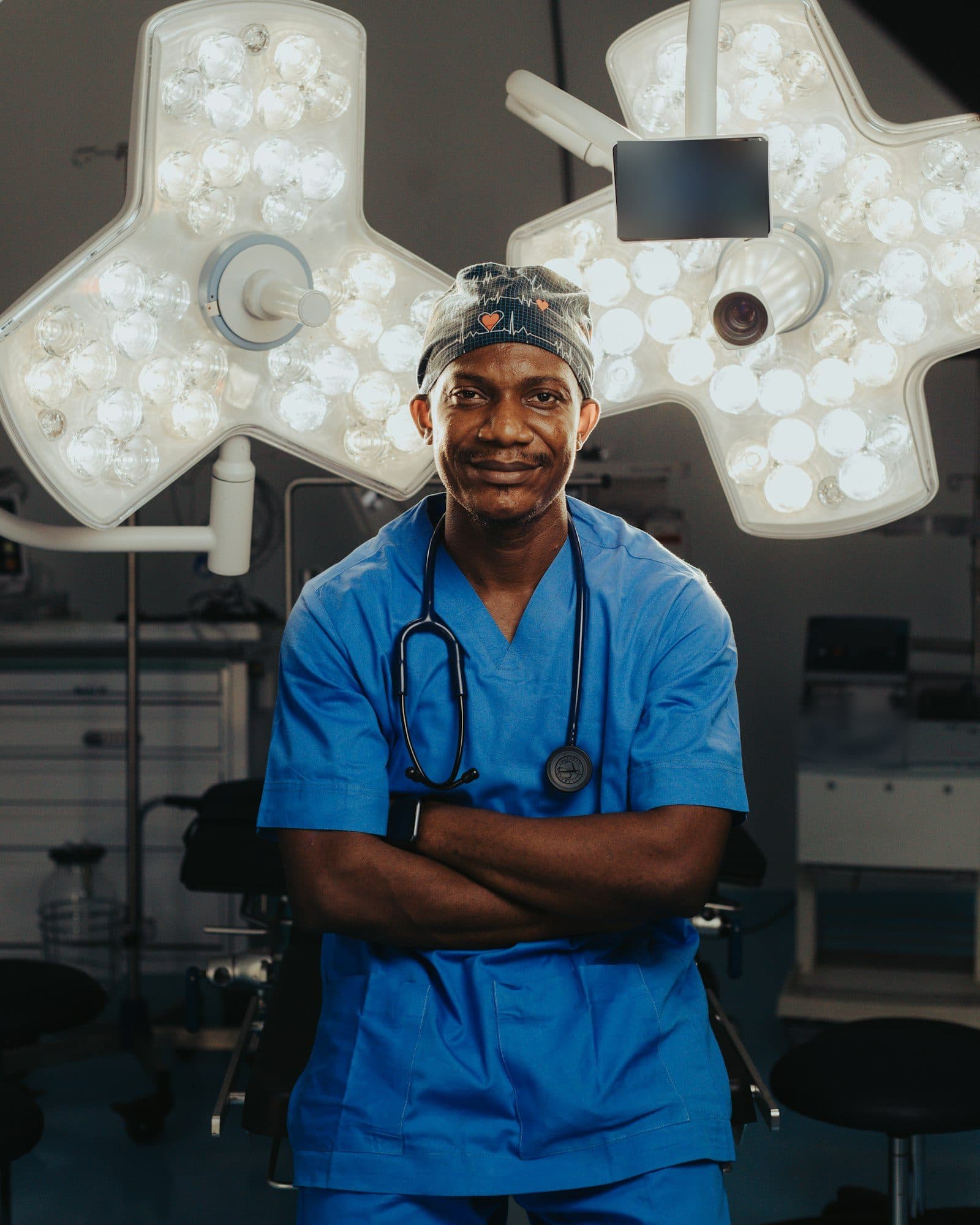 A surgeon in scrubs stands beneath the lights of an operating theatre.