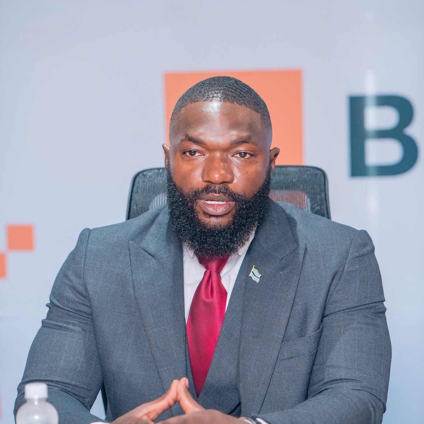 A man in a suit seated at a boardroom table, facing the camera.