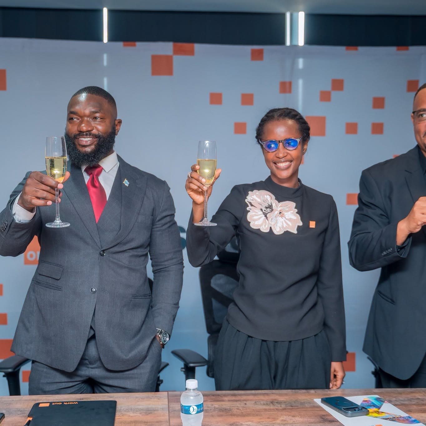 Three people raising glasses at a boardroom table after the signing.